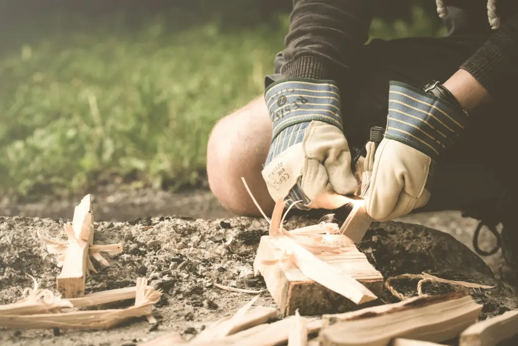 Mann beim Bushcraft in Deutschland, macht Feuer mit Feuerstahl im Wald