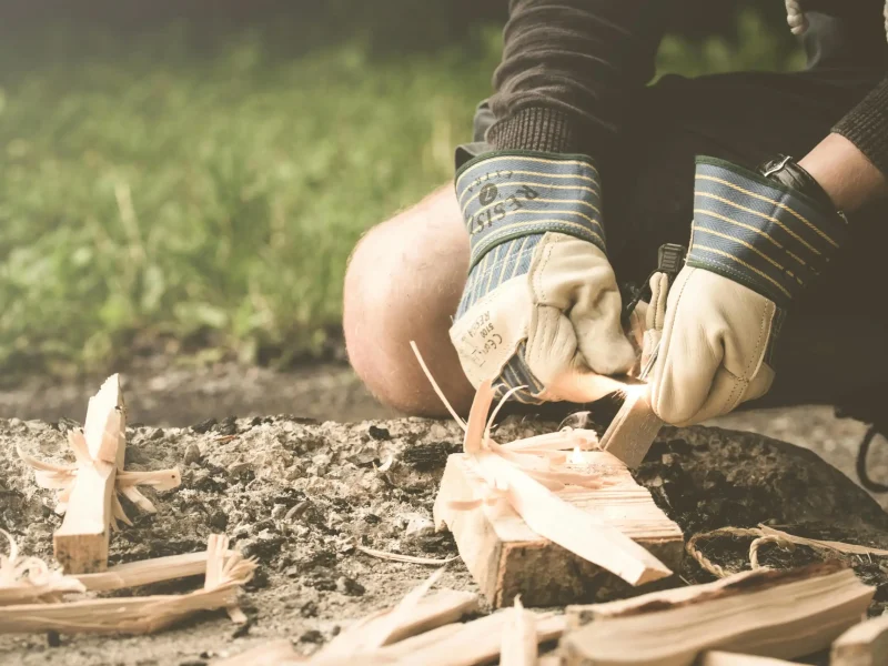 Mann beim Bushcraft in Deutschland, macht Feuer mit Feuerstahl im Wald
