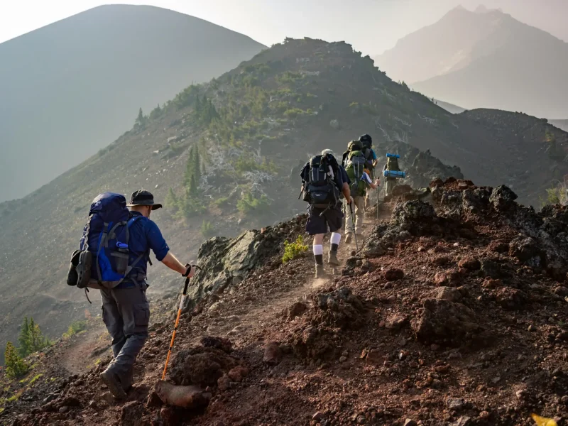 Menschen beim Wandern in einer alpinen Berglandschaft mit Weitblick