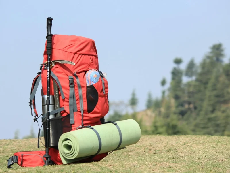 Wildcamping: Roter Rucksack mit befestigter Isomatte für Outdoor-Abenteuer