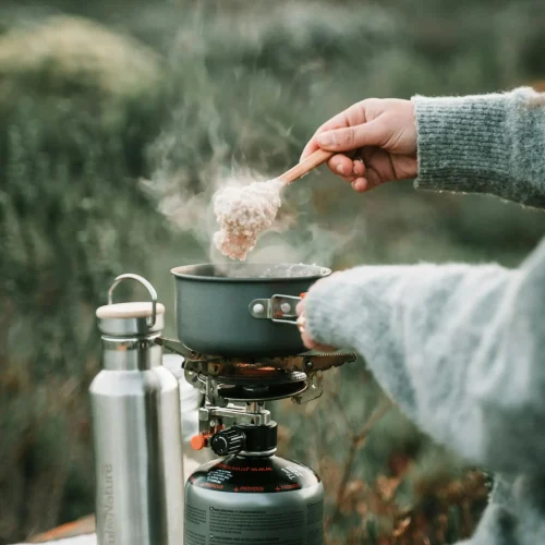 Wildcamping-Küche – Gaskocher in Aktion beim Outdoor-Kochen Wildcamping: Kleiner Gaskocher erhitzt Topf für warme Mahlzeit im Freien